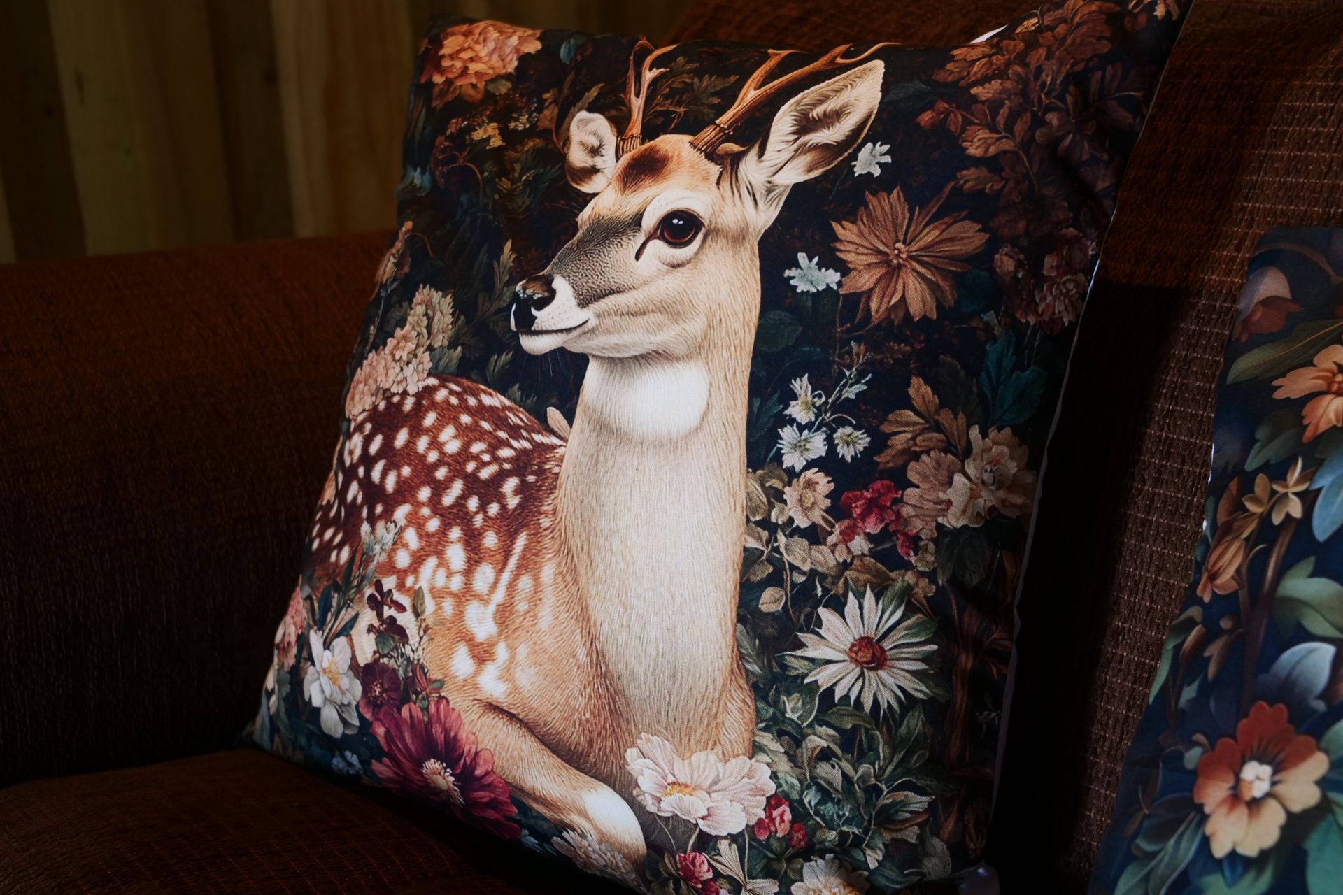 Deer illustration on a floral throw pillow on a sofa
