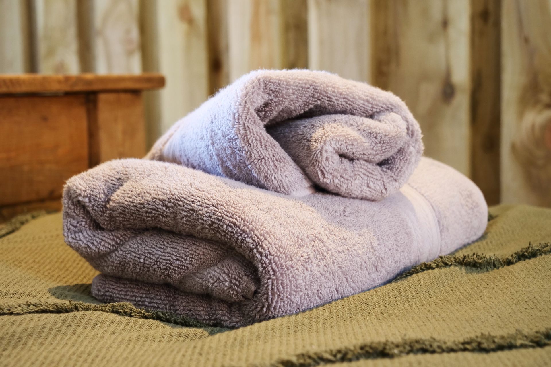Two folded towels, one lavender and one gray, stacked on a textured surface