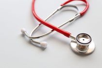 Red and silver stethoscope on a light gray surface