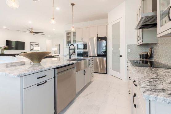 Modern kitchen with stainless steel appliances, white cabinets, granite countertops, and island.