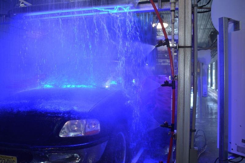 A car is being washed in a car wash with blue lights.