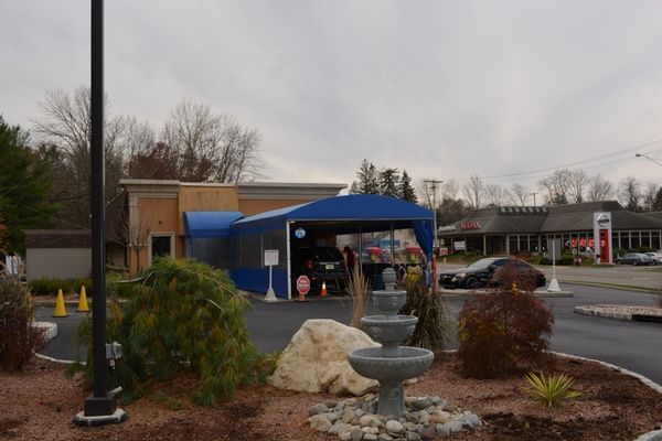 A car wash with a blue awning and a fountain in front of it