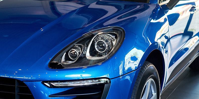 A blue porsche macan turbo is parked in a showroom.