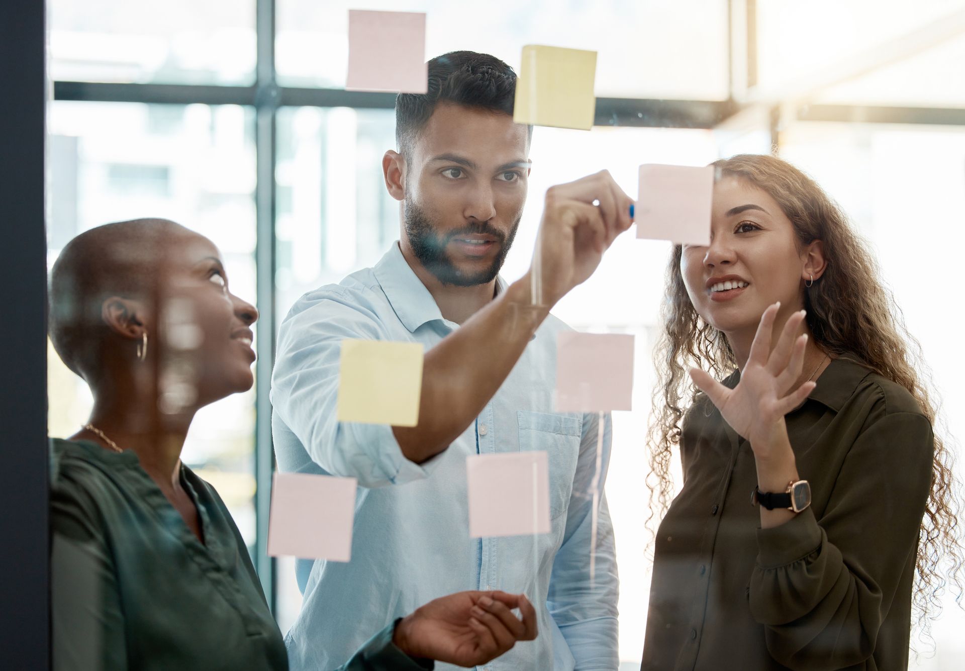 A Group of People Are Looking at Sticky Notes on A Glass Wall.