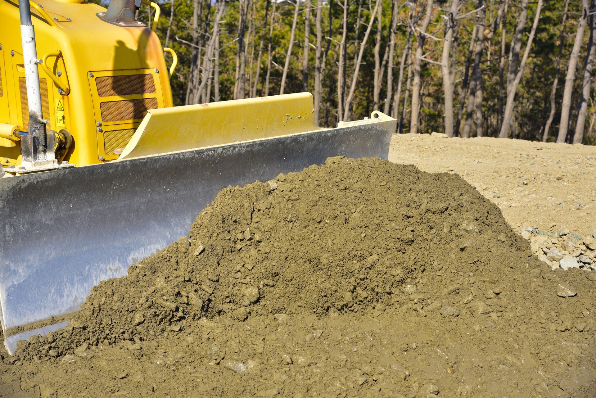 A bulldozer is pushing a pile of dirt in a field