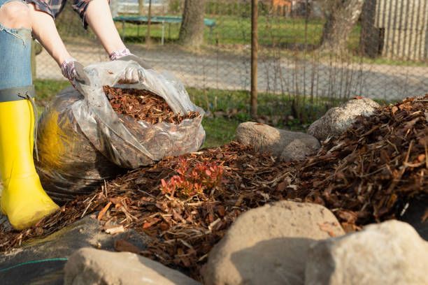 A person wearing yellow boots is holding a bag of mulch.