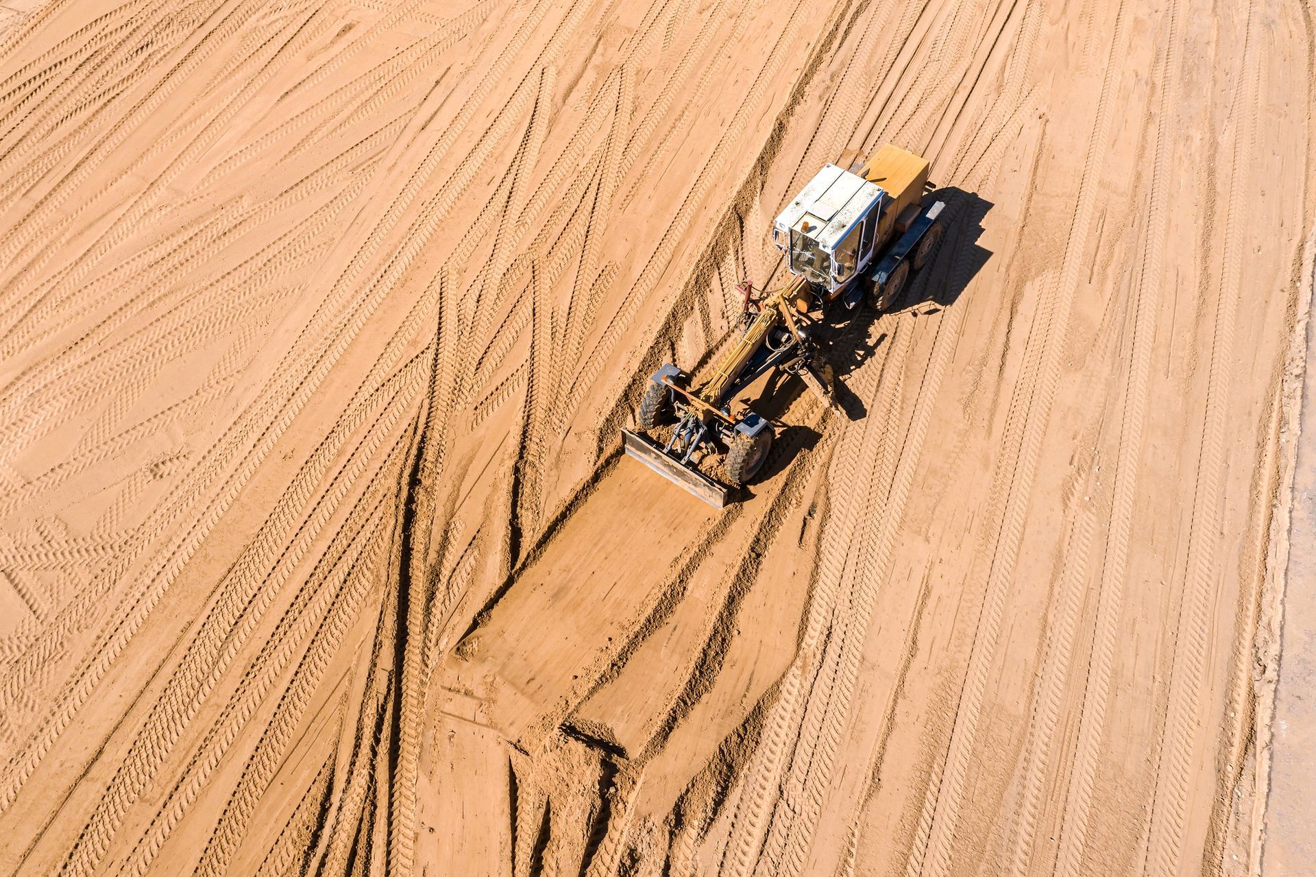 An aerial view of a bulldozer moving dirt in a field
