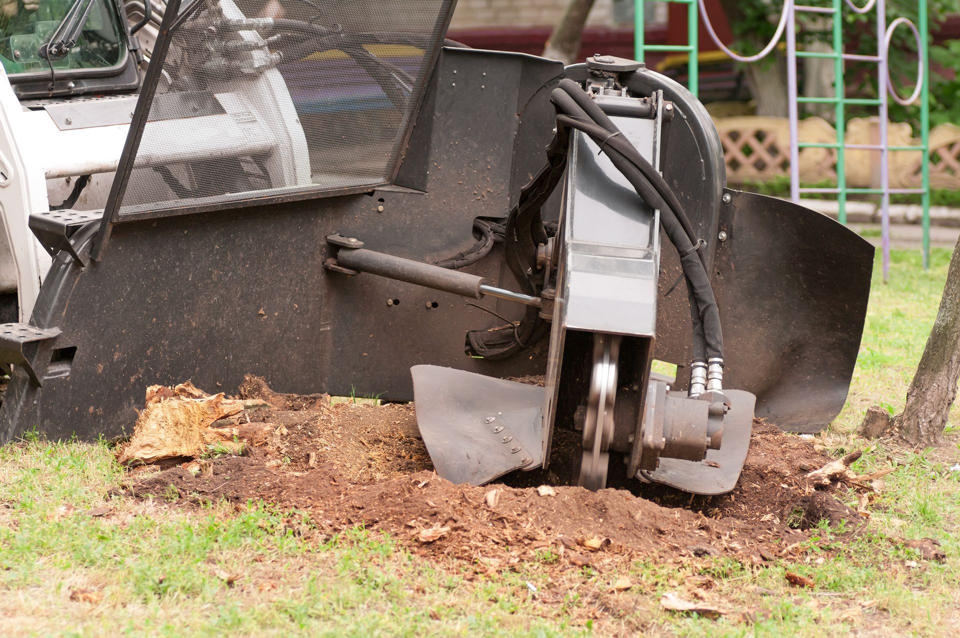 A machine is cutting a tree stump in the ground.