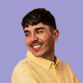 The man is wearing a yellow shirt and smiling.