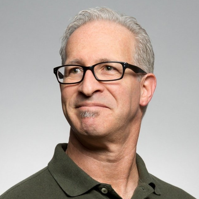 A man wearing glasses and a green shirt is smiling