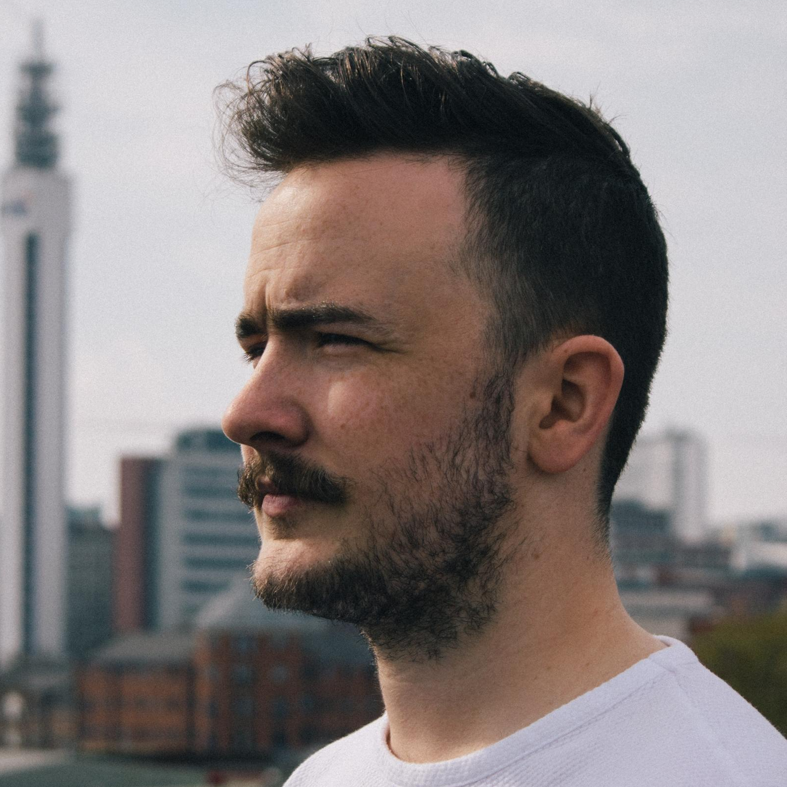 A man with a beard and mustache is wearing a white shirt