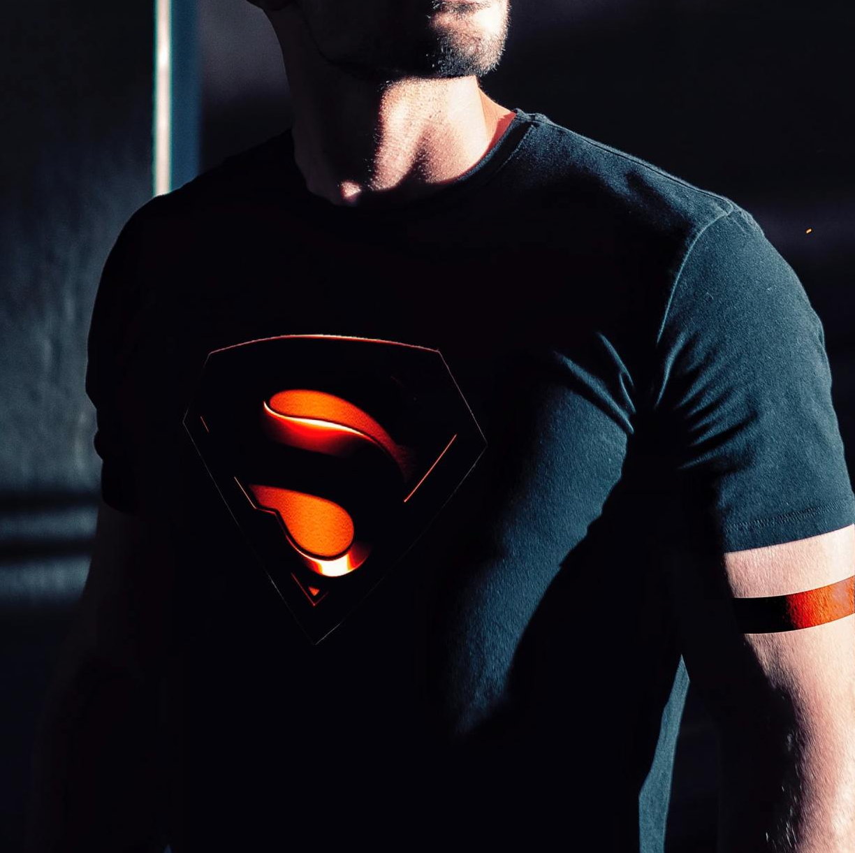 A man wearing a black shirt with a superman logo on it