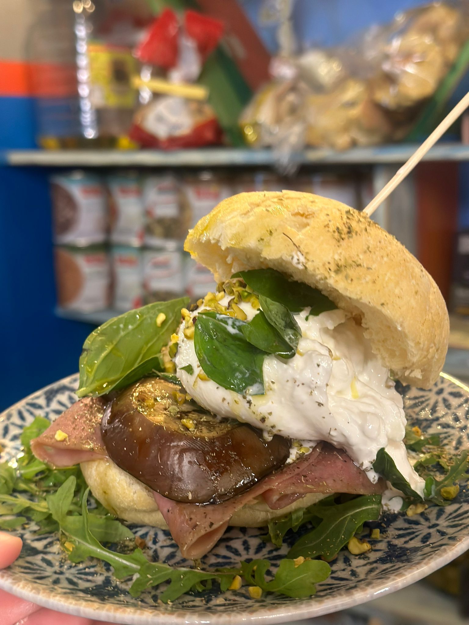 Una persona tiene in mano un piatto di cibo con un panino sopra.