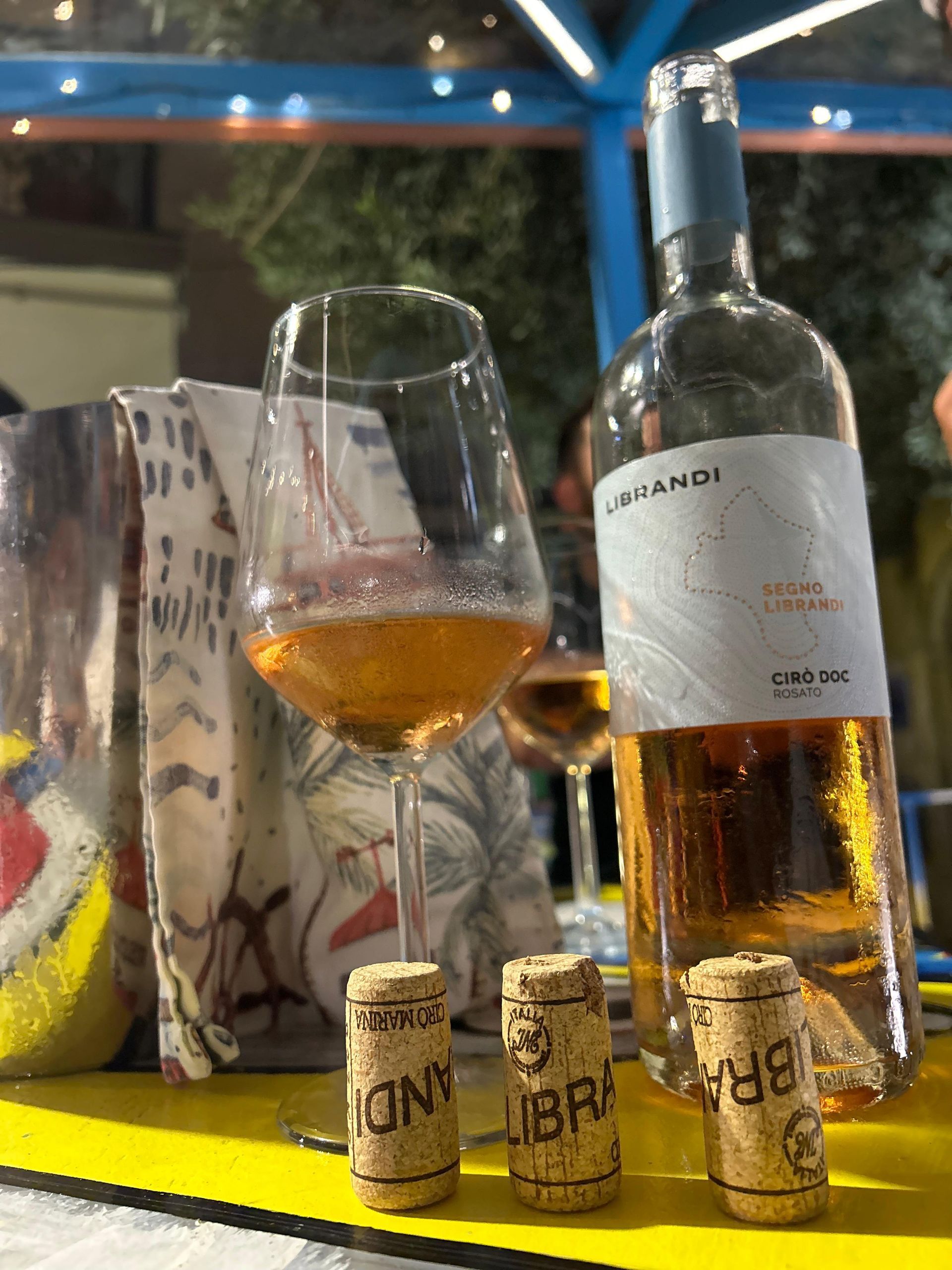 Una bottiglia di vino e un bicchiere di vino sono su un tavolo.