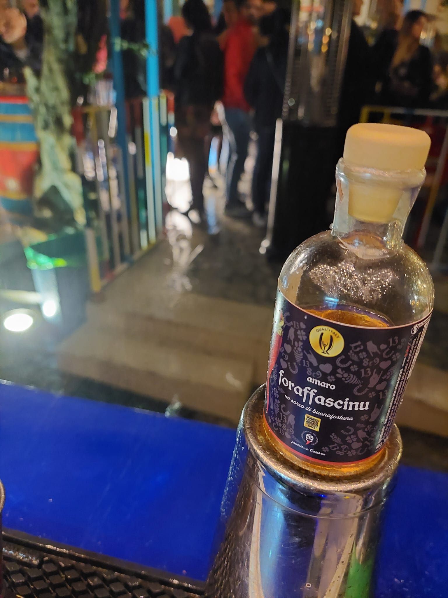 Una bottiglia di alcol è appoggiata su un tavolo blu.