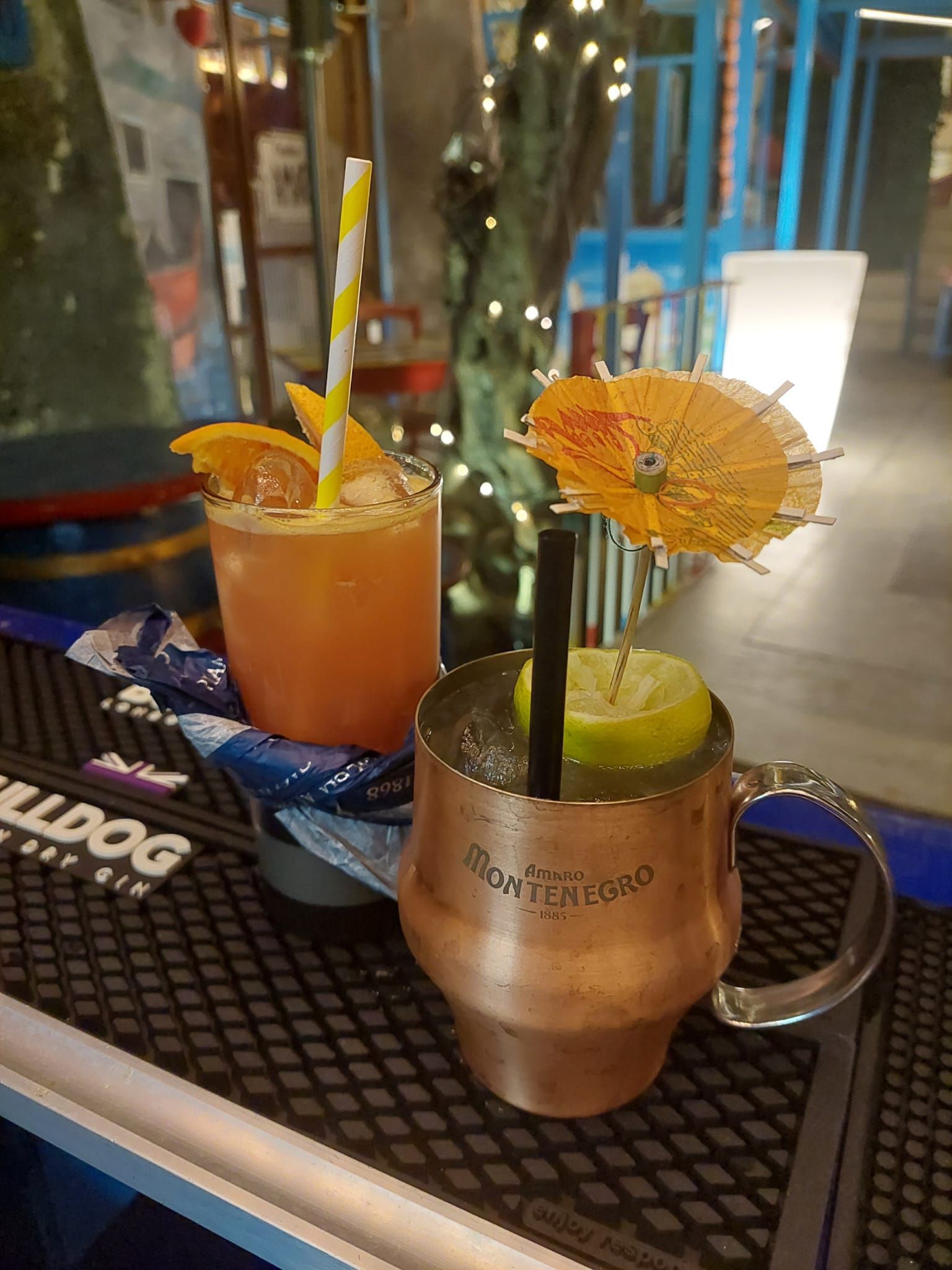 Due drink sono appoggiati su un bancone del bar, con delle cannucce al loro interno.