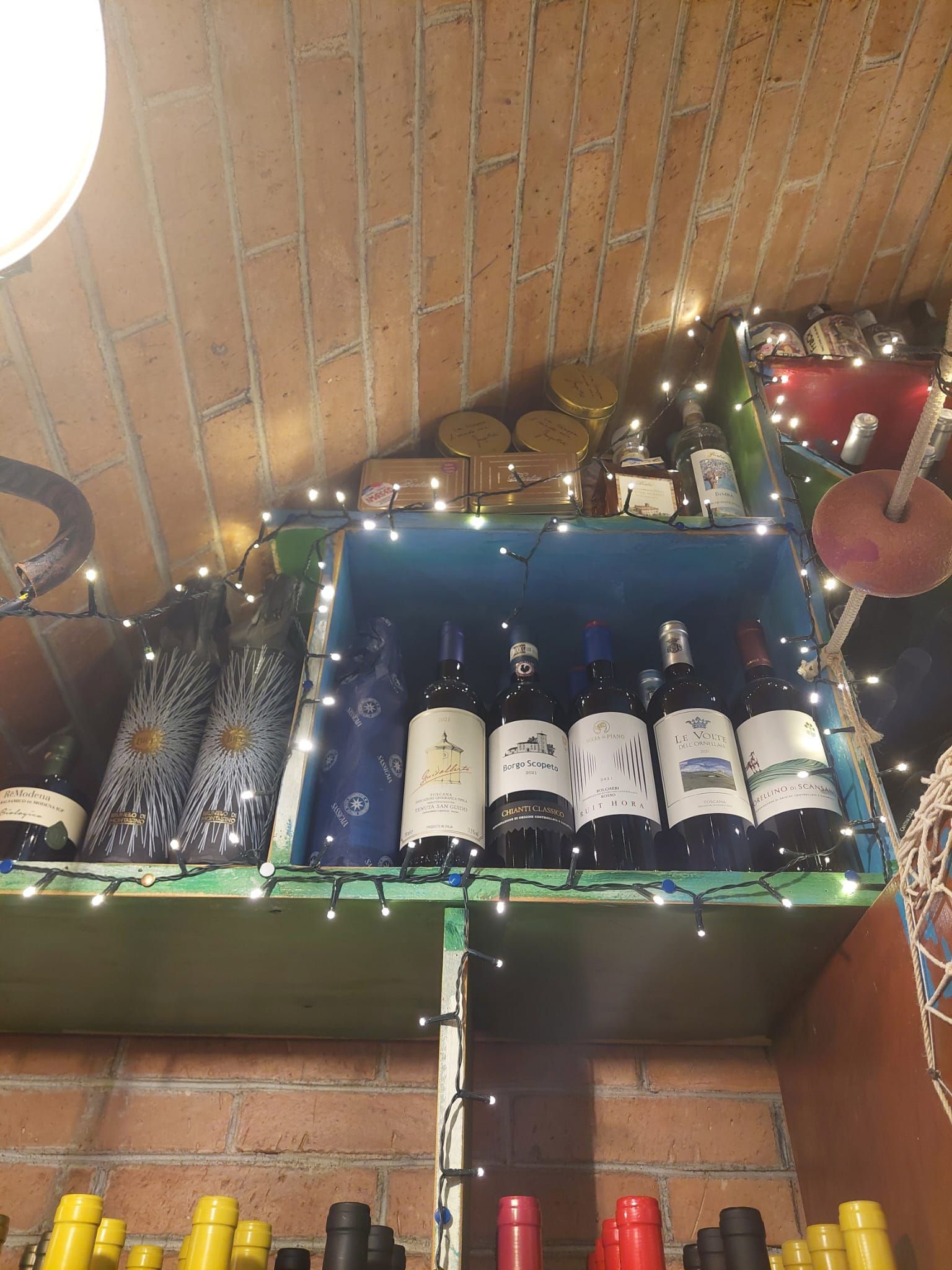 Uno scaffale pieno di bottiglie di vino e luci di Natale.