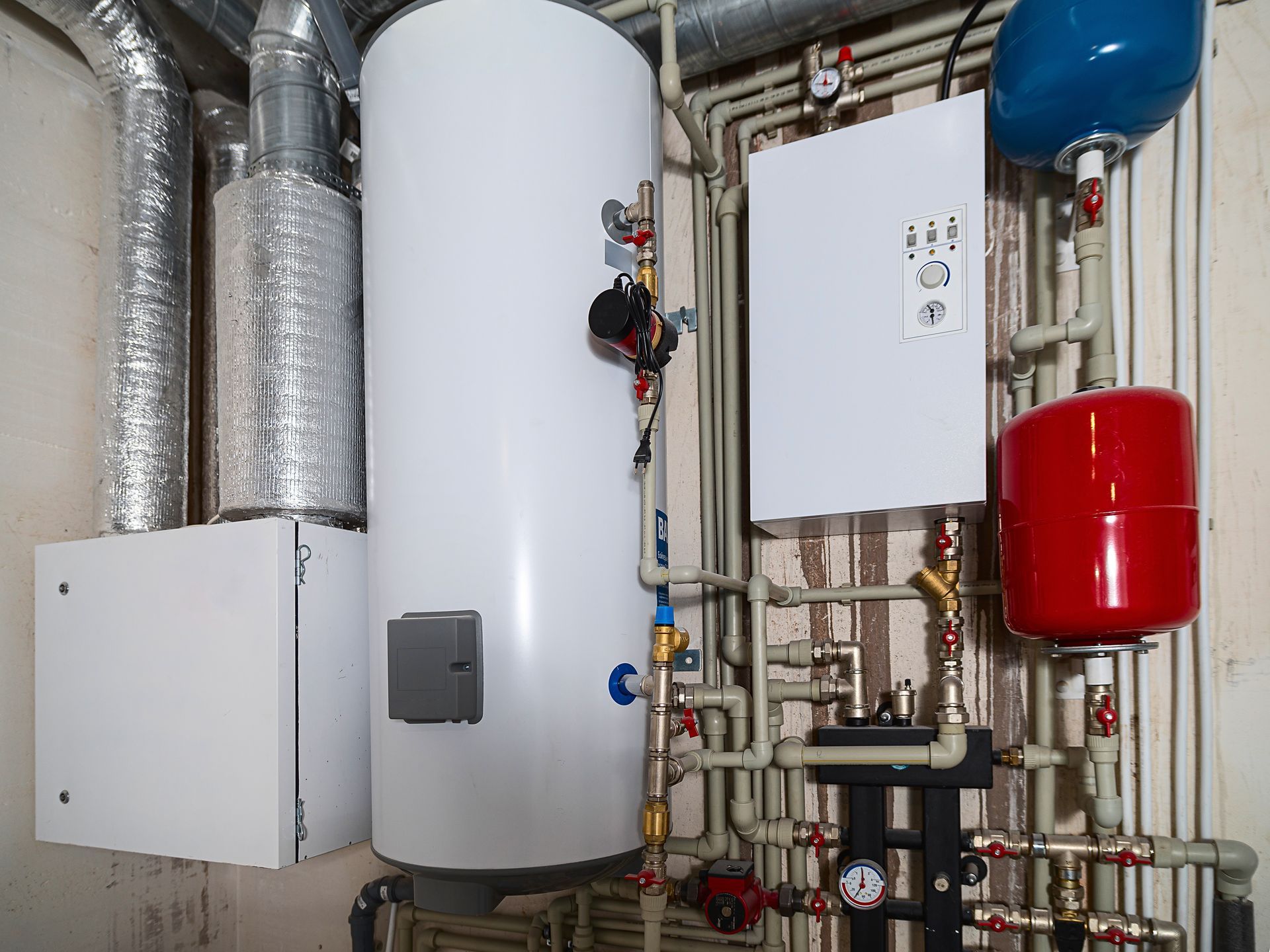 Close-up of a professional commercial water heater installation featuring a white tankless unit with stainless steel flexible hosing.