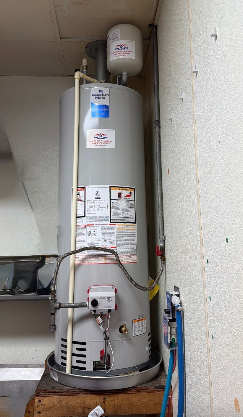 Tall white water heater tank in a utility closet with pipes and labels visible