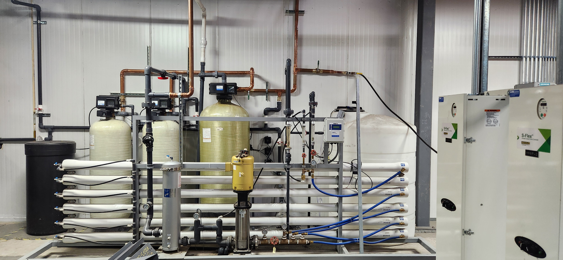 A commercial water filtration system featuring large tanks, pipes, and control panels in an industrial setting.