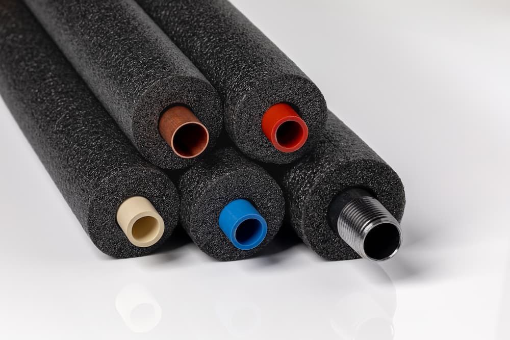 Close-up of insulated plumbing pipes in various colors, showcasing professional pipe lining and insulation services in Jacksonville, FL.
