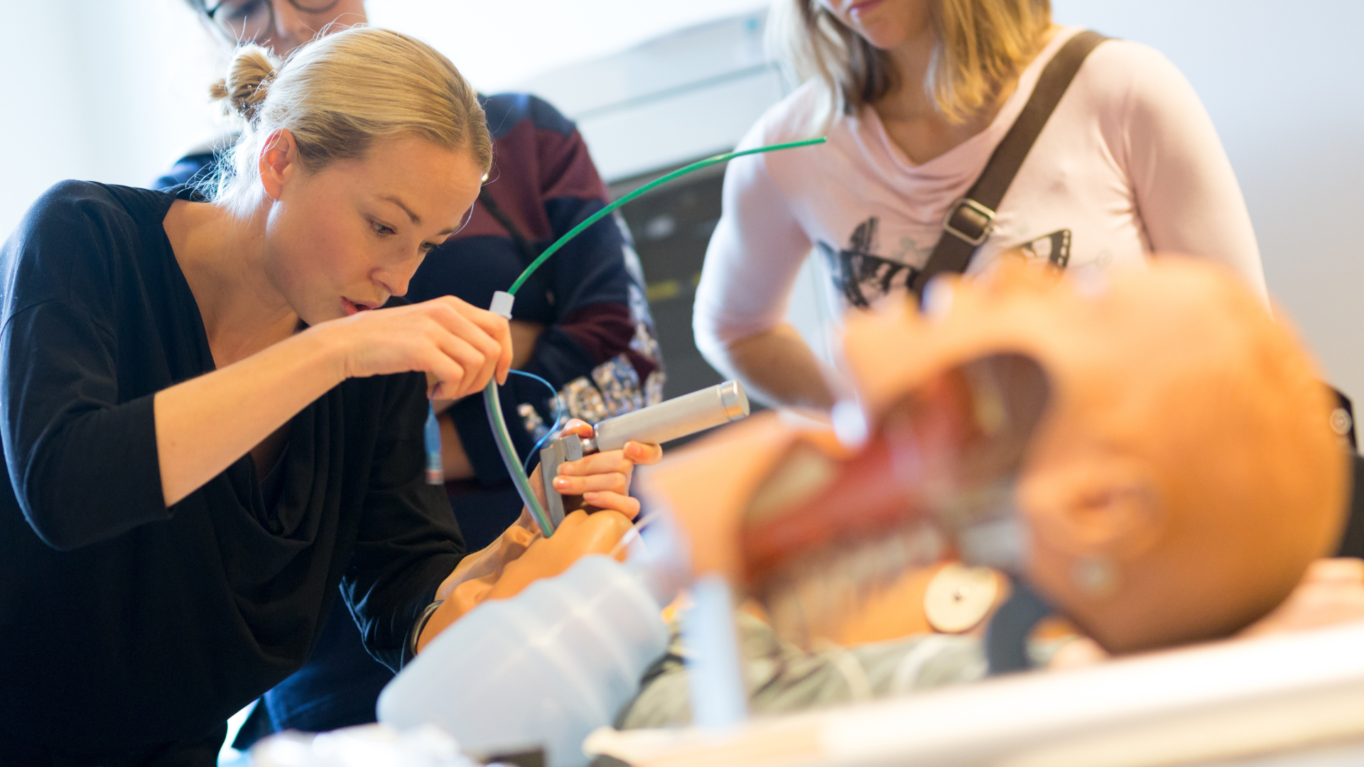 A woman is using an oxygen mask on a mannequin.