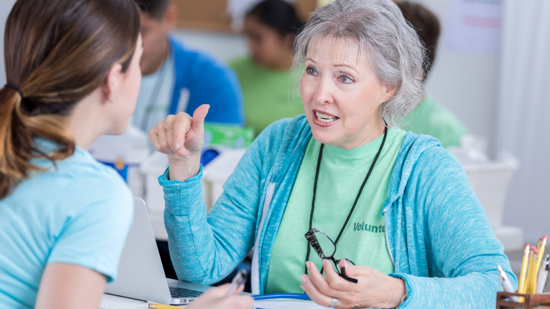 Two women are sitting at a table talking to each other.