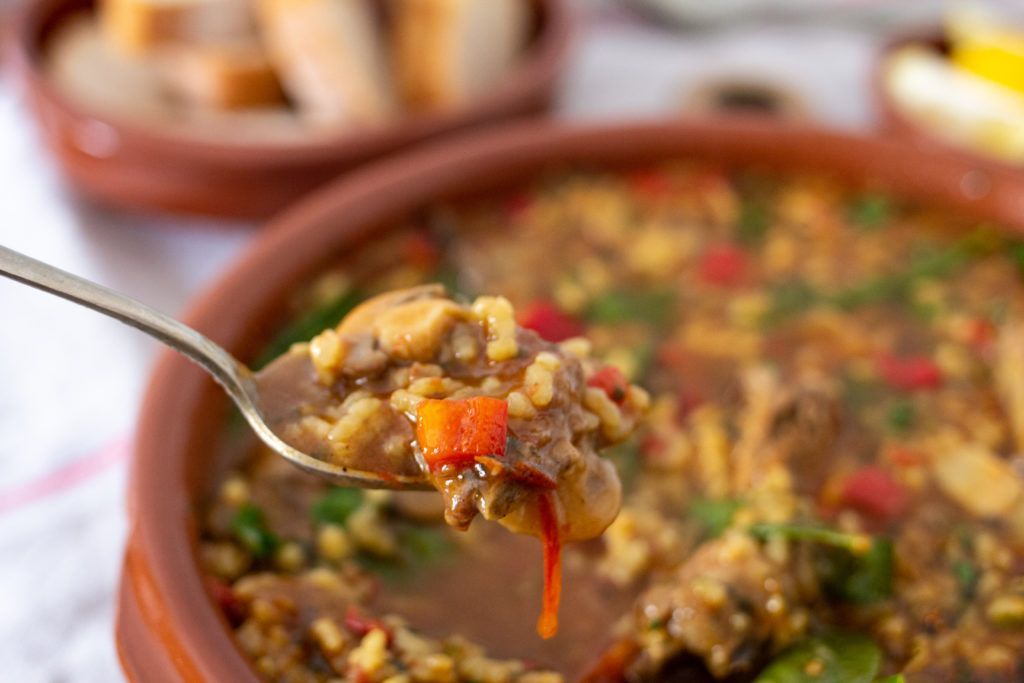 Una persona sostiene una cuchara en un tazón de sopa.