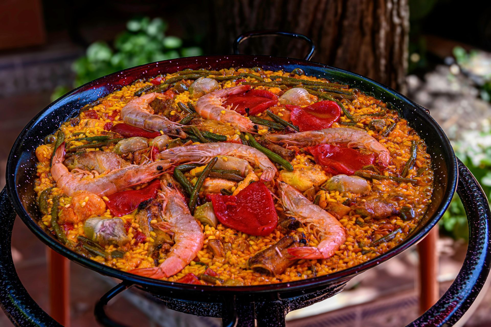 Una sartén de paella con camarones y verduras sobre una mesa.