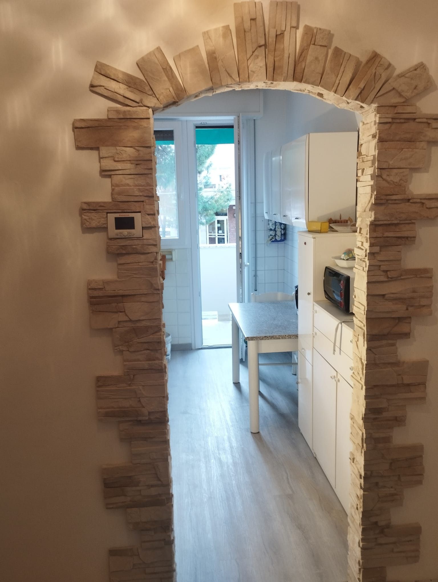 Un corridoio con un arco in pietra che conduce ad una cucina