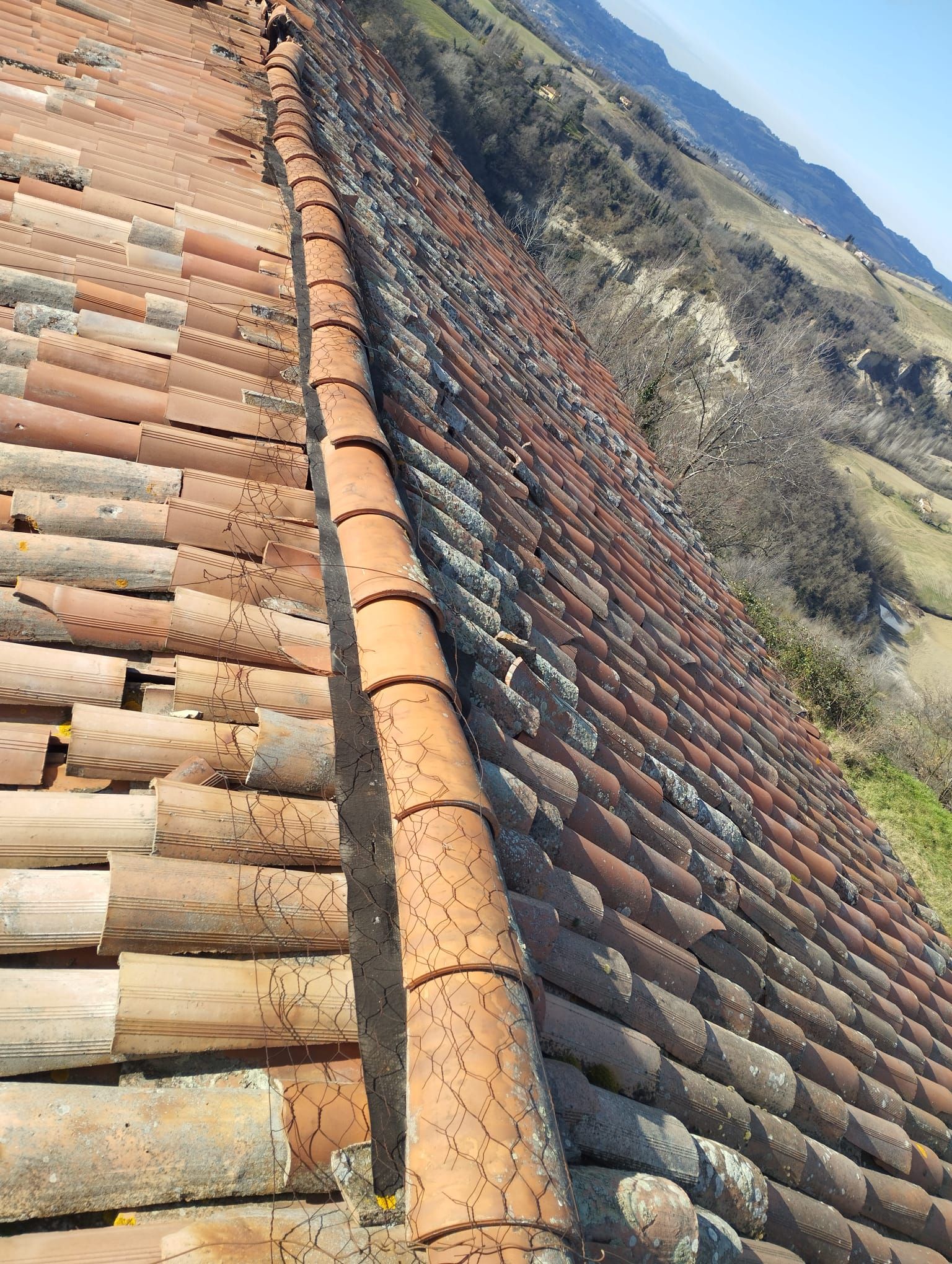 Un tetto con tante tegole e una valle sullo sfondo.