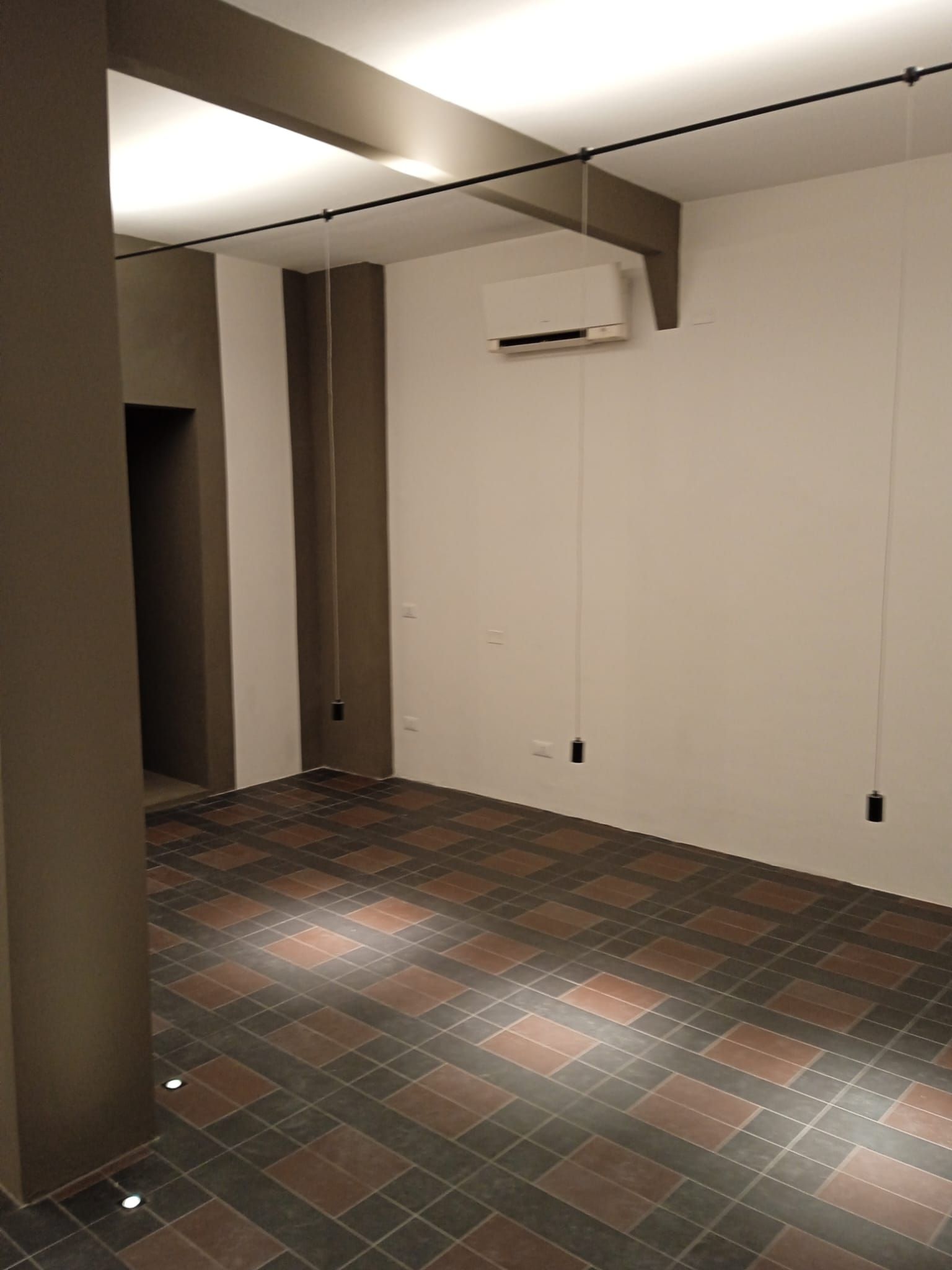 Una stanza vuota con pavimento piastrellato e ventilatore a soffitto.