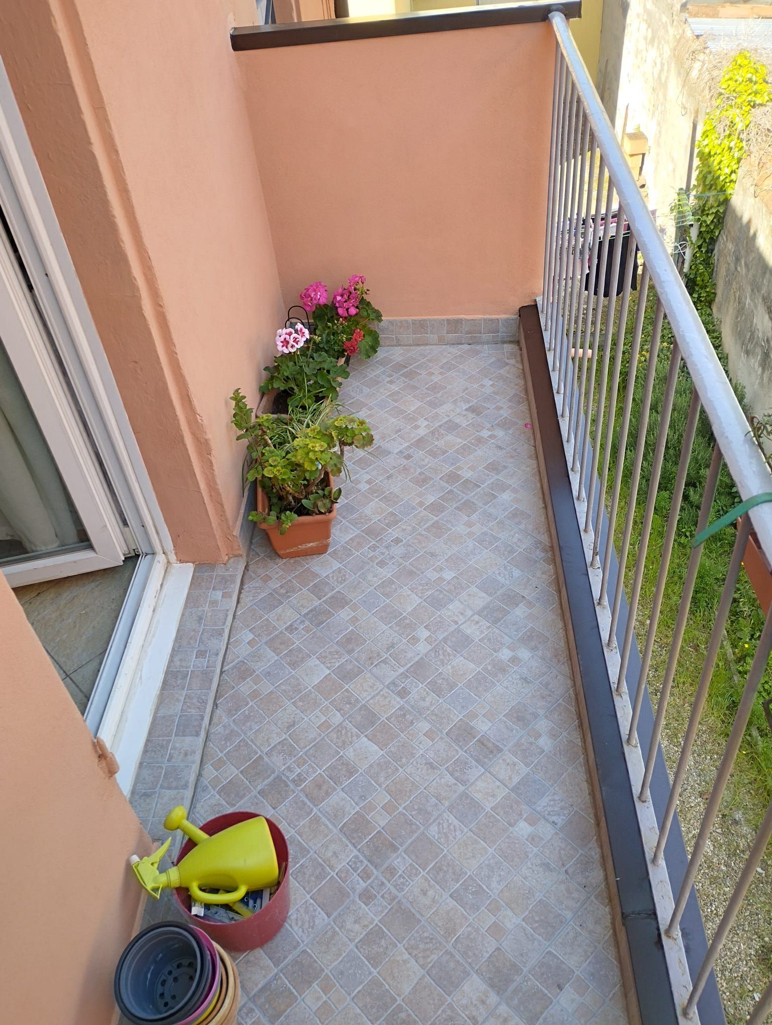Un balcone con piante in vaso e un annaffiatoio.