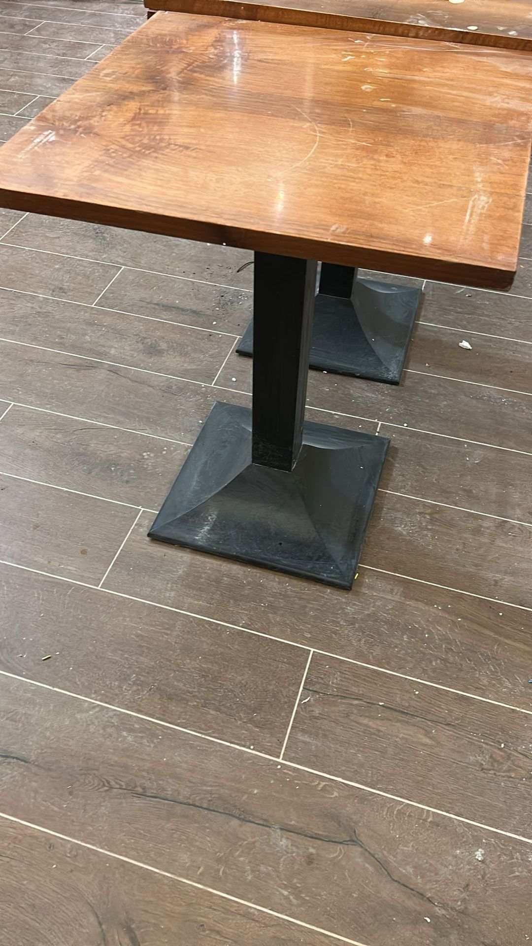 Macchina lavapavimenti con copertura turchese su un pavimento piastrellato in un corridoio, accanto alle gambe di una persona.