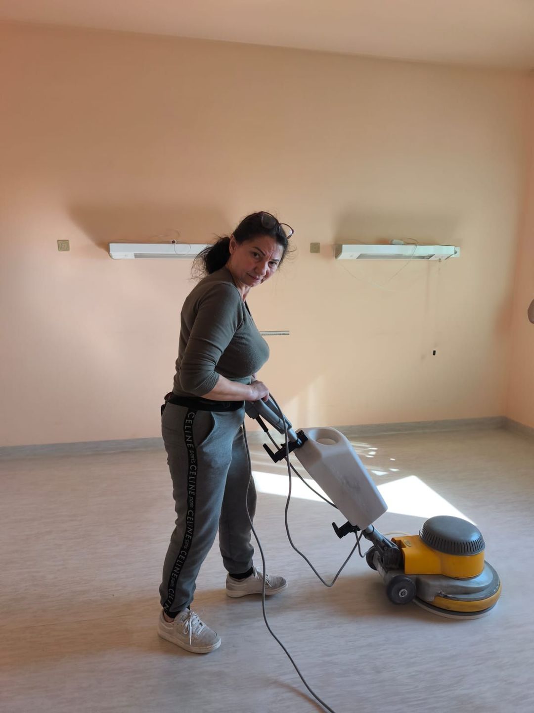 Una persona passa l'aspirapolvere su un pavimento ricoperto di moquette in una stanza in fase di pulizia.