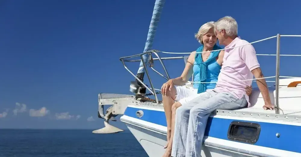 A man and a woman are sitting on the side of a boat in the ocean.