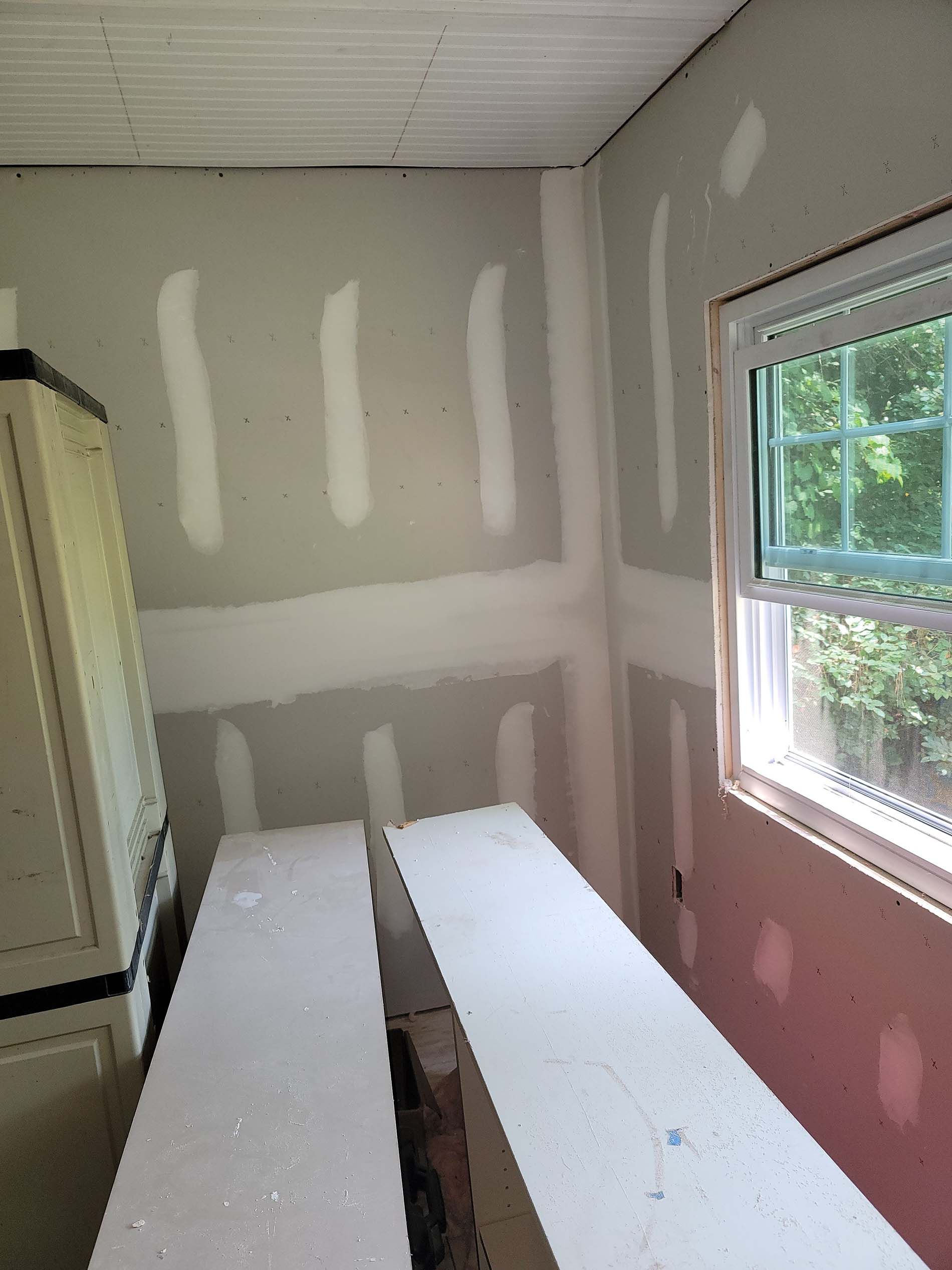 A room with drywall on the walls and a window.