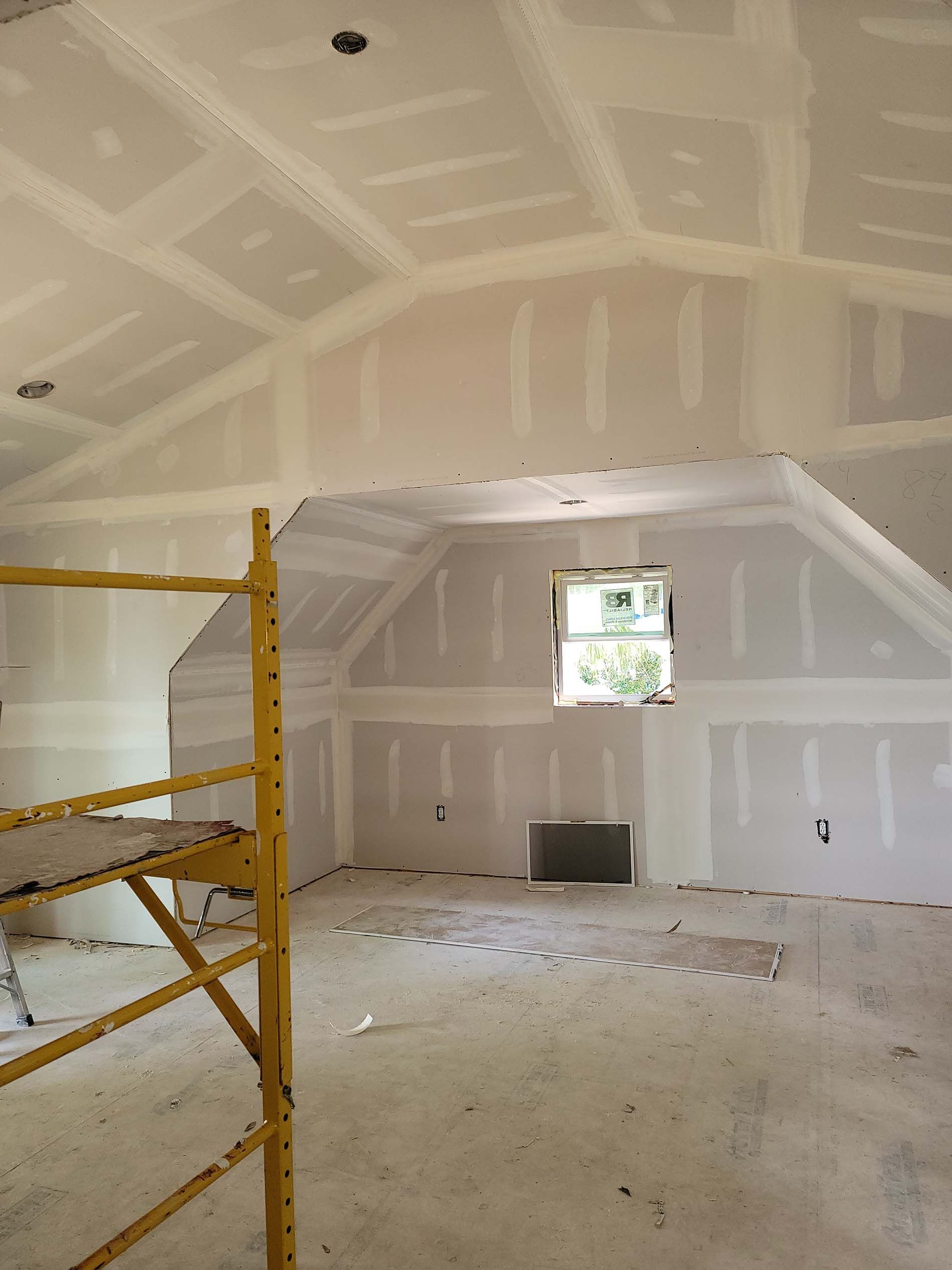 An empty room with a yellow scaffolding and a window.