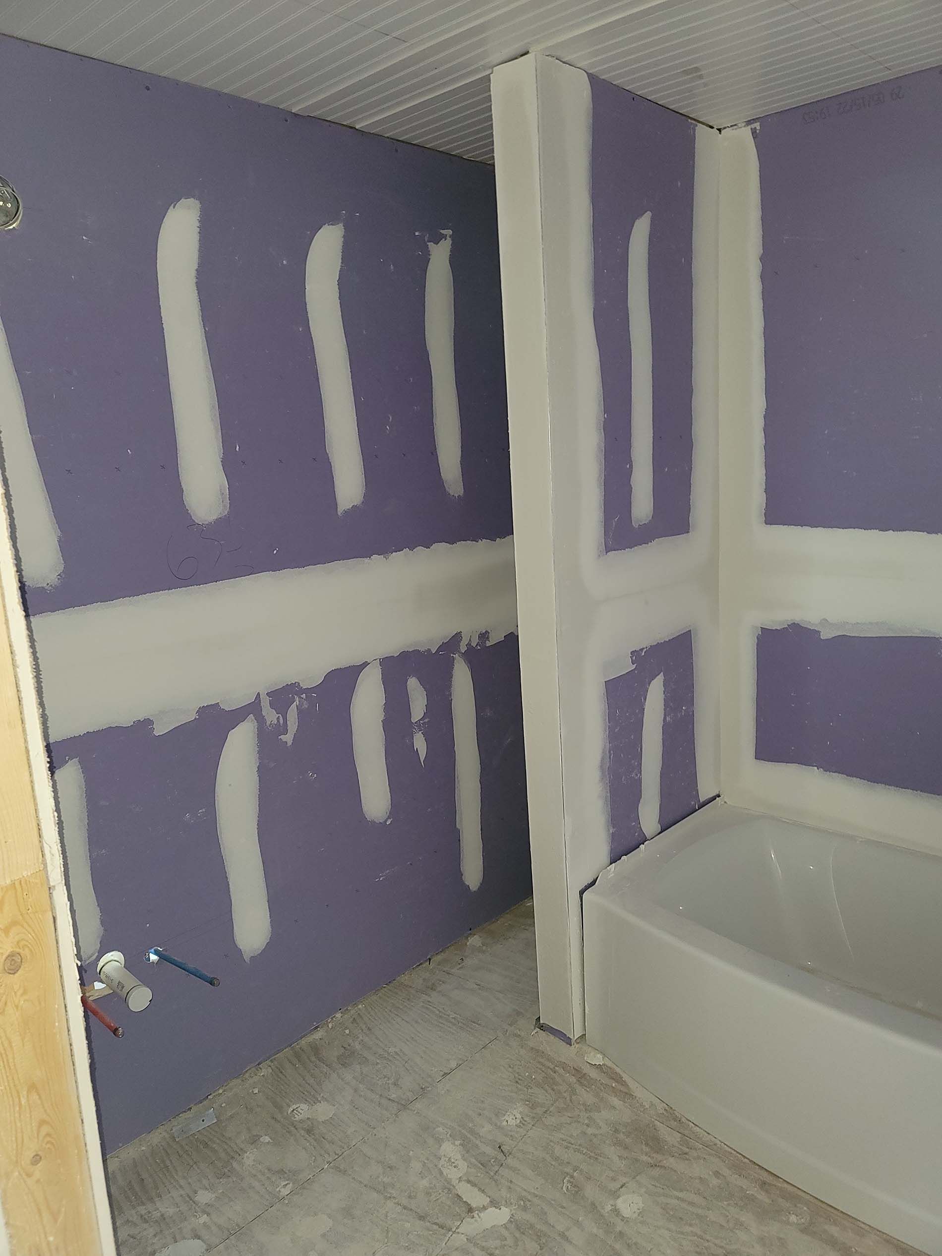 A bathroom with purple walls and a white bathtub.