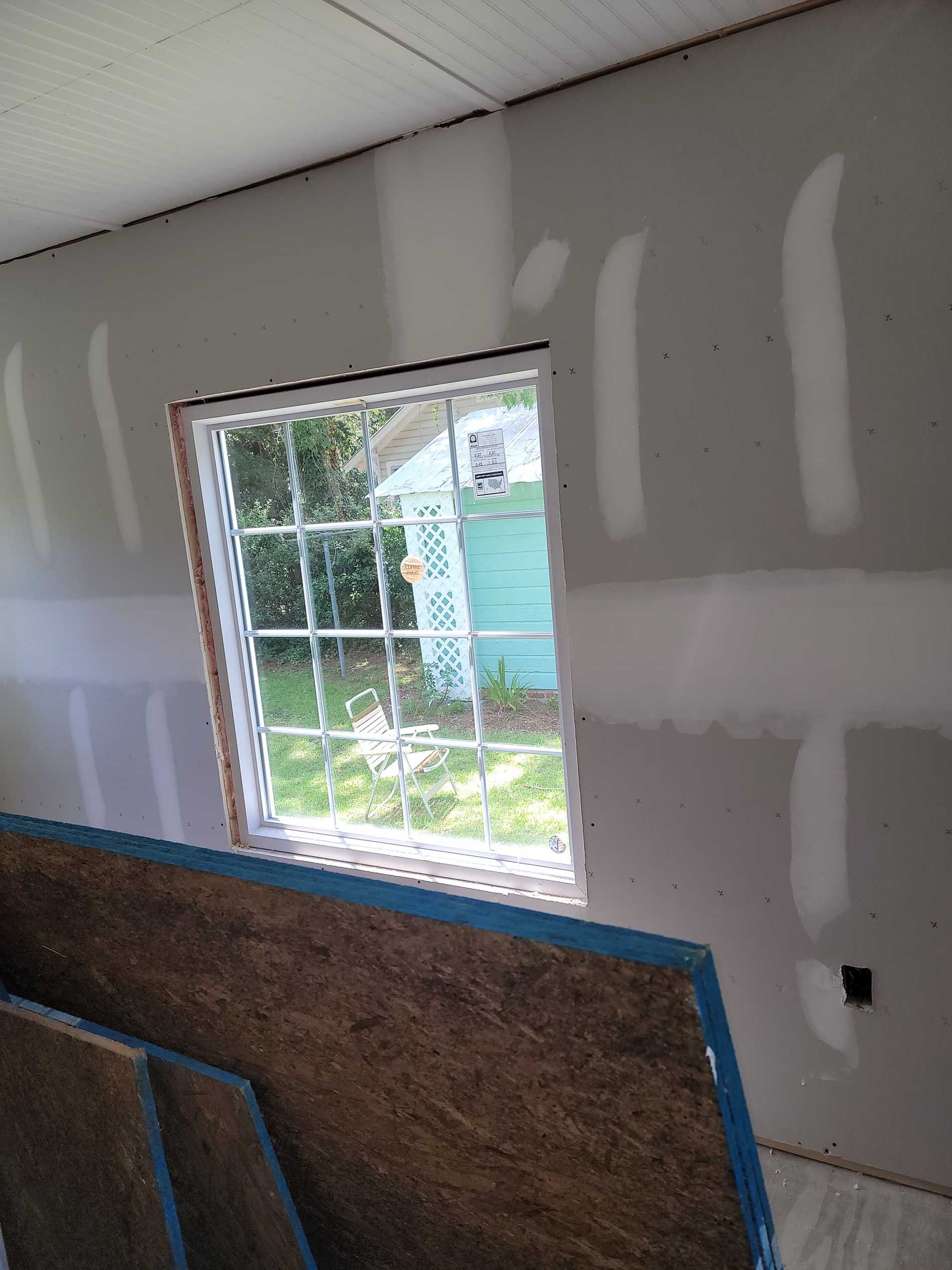 A room with a window and a shed in the background.