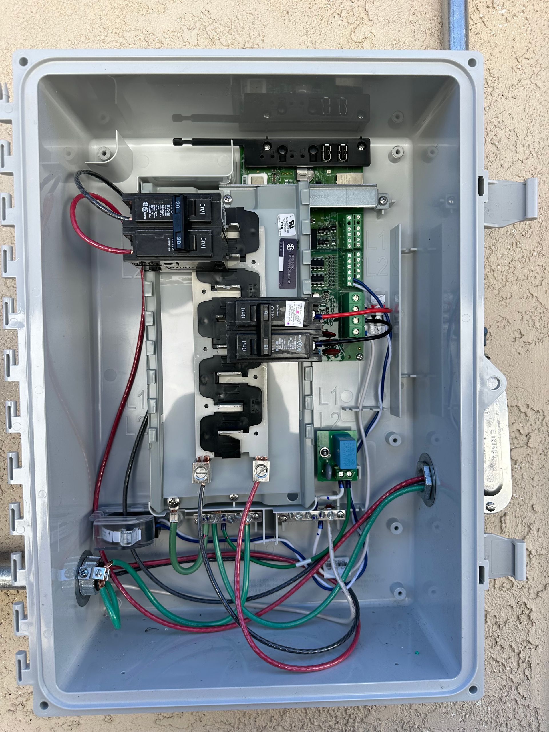 A box with a lot of wires in it is sitting on a wall.