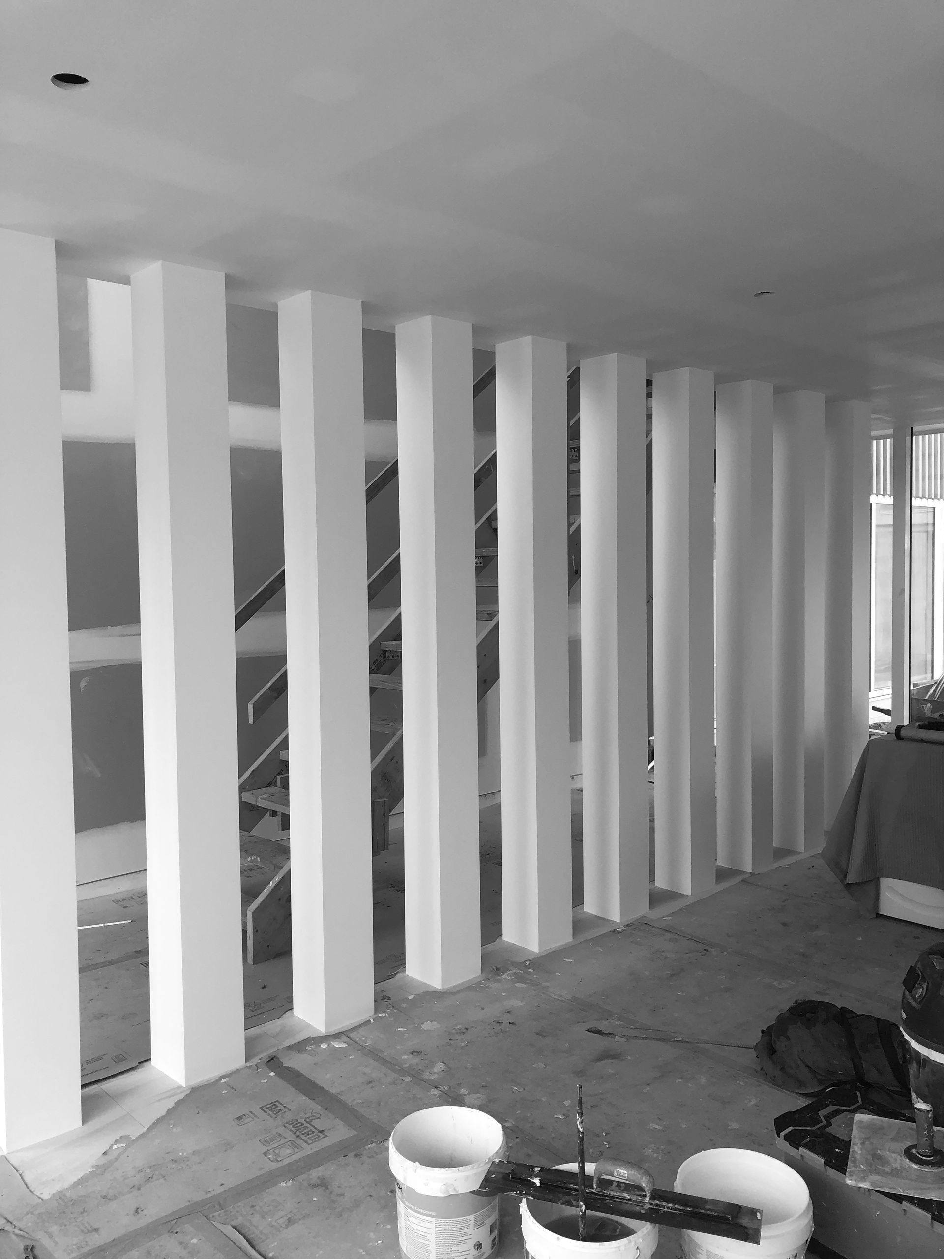 A Black And White Photo Of A Room With White Pillars And A Staircase — MC Plastering In Fingal Bay, NSW