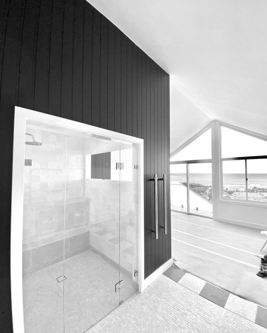 A Black And White Photo Of A Bathroom With A Glass Shower Door — MC Plastering In Fingal Bay, NSW