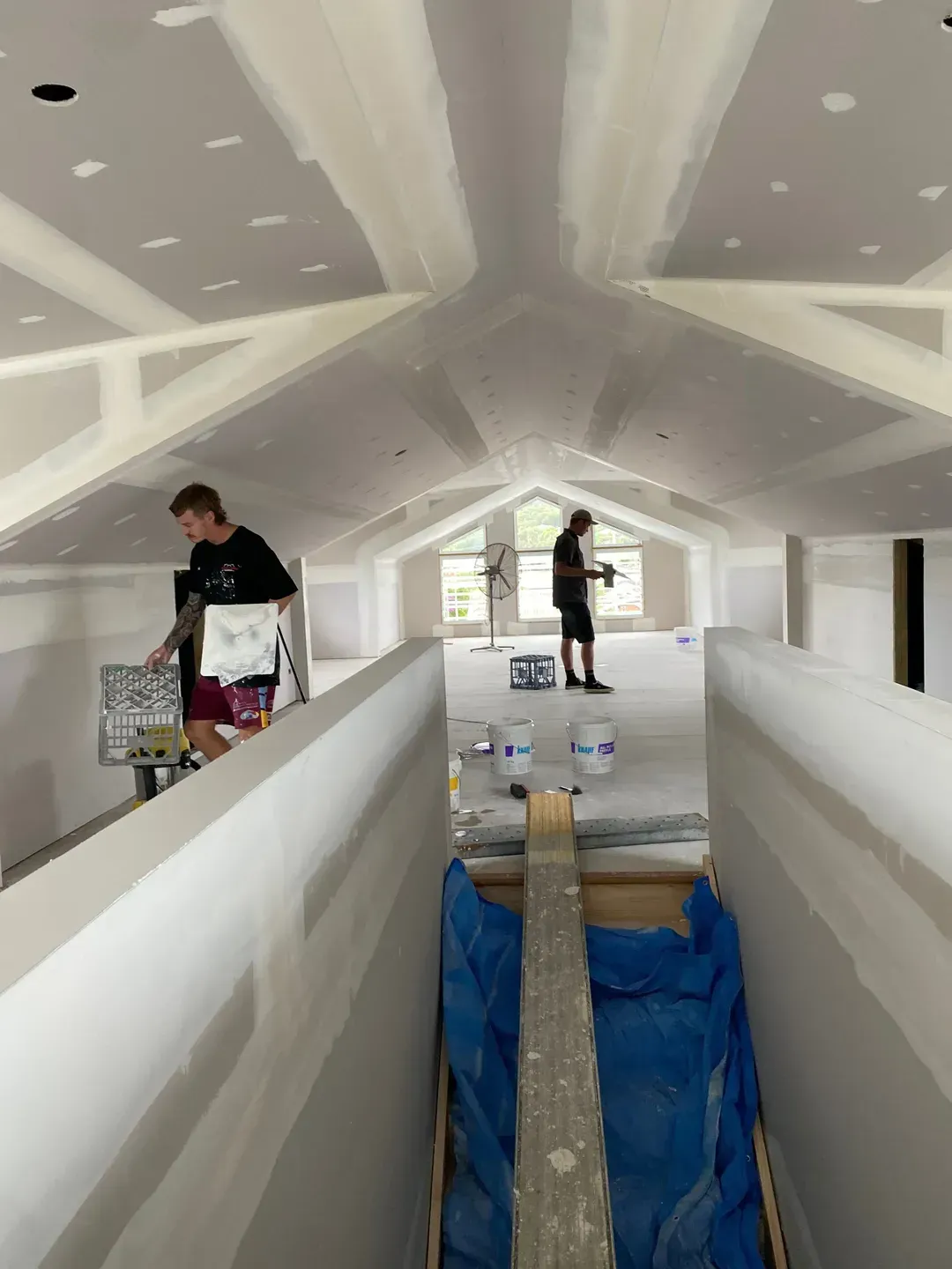 A Man Is Standing In A Room With A Blue Tarp On The Floor — MC Plastering In Fingal Bay, NSW
