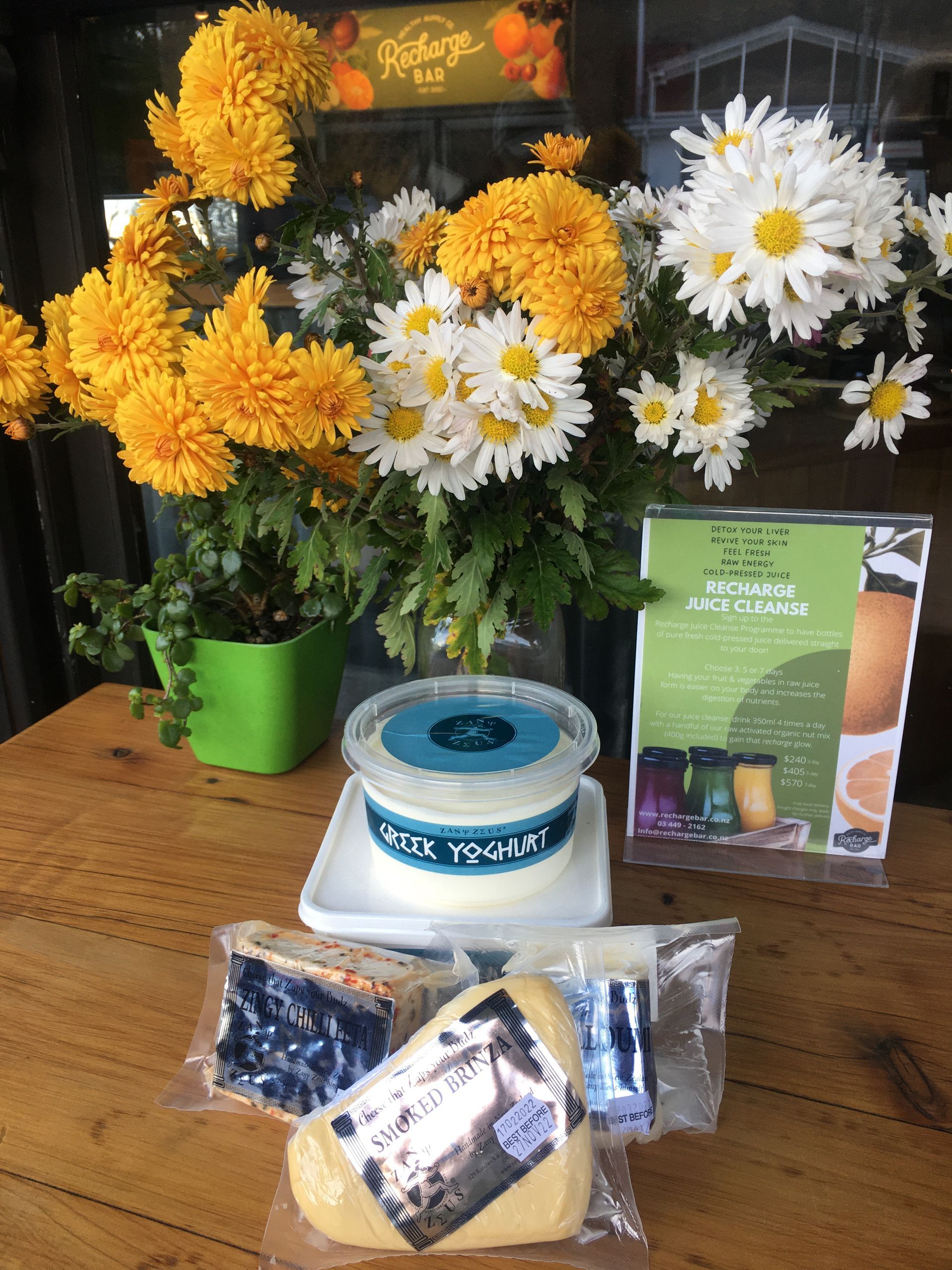 a container of greek yoghurt sits on a table next to flowers, clyde, best food, best coffee, best cafe, organic, groceries