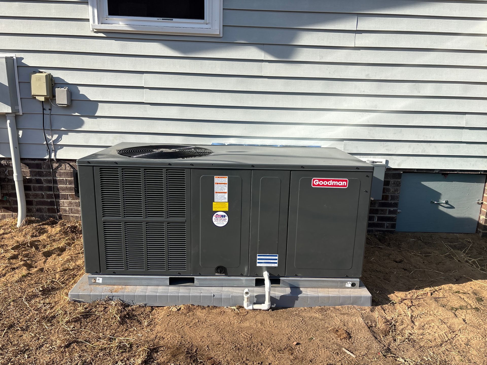 Exterior air conditioning unit next to a light blue house.