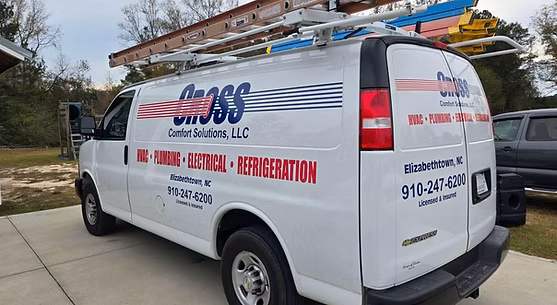 A white van with a ladder on top of it is parked in a driveway.