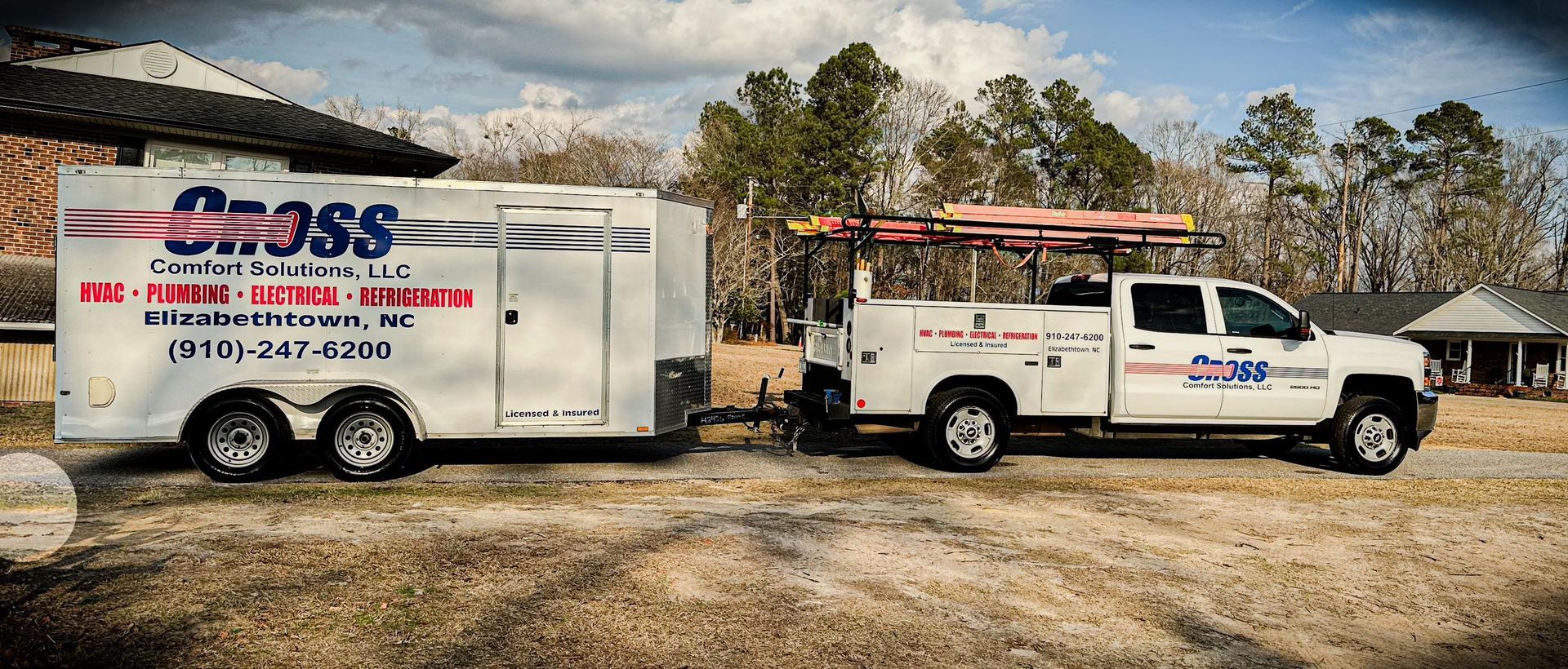 A white truck with a trailer attached to it is parked in front of a house.