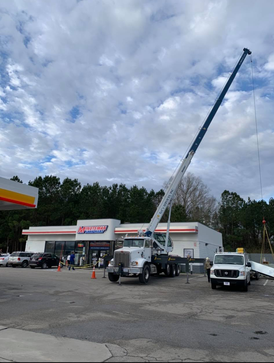 A large crane is parked in front of a gas station
