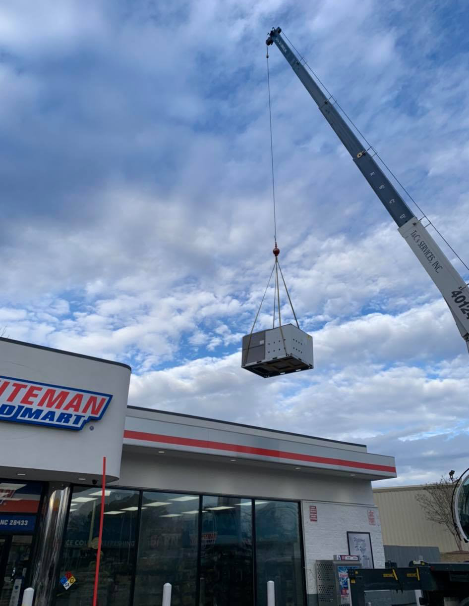 A crane is lifting a piece of equipment from a building.